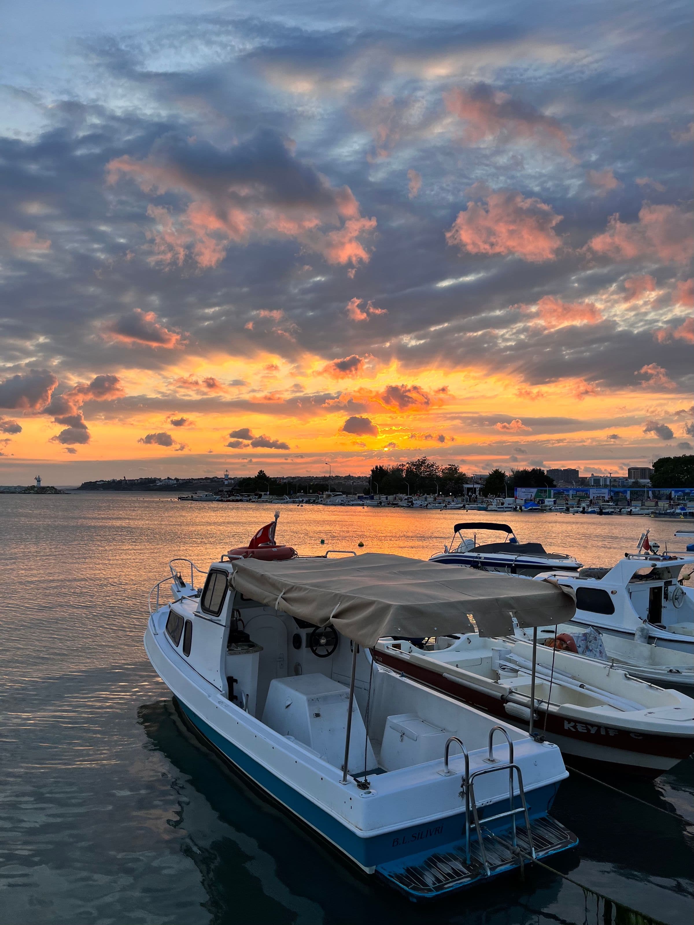Working coastal harbor with boats moored along the shore at sunset