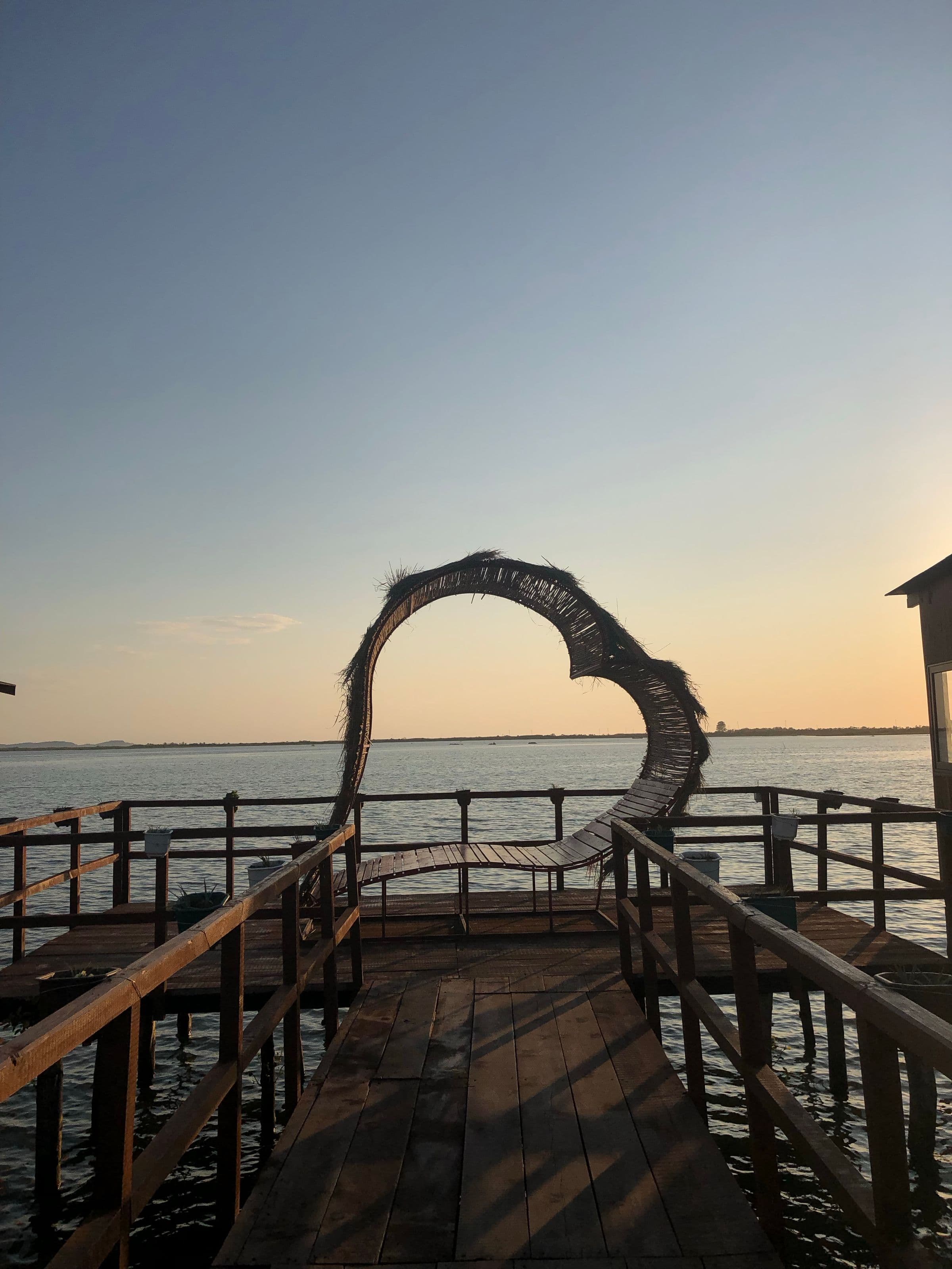 Wooden pier stretching out over calm bay waters at dusk